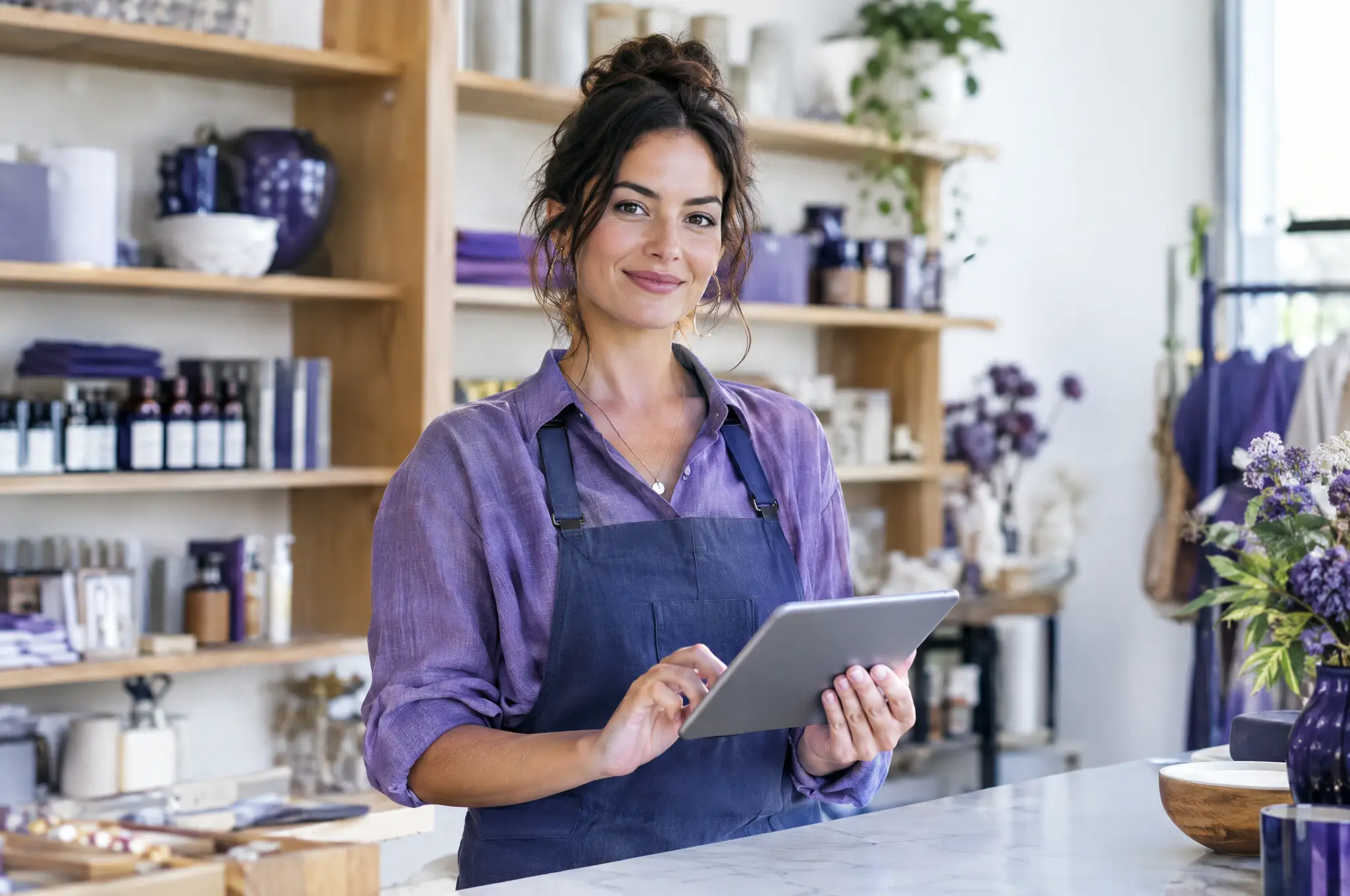 A shop owner checking customer chats on a tablet in her store